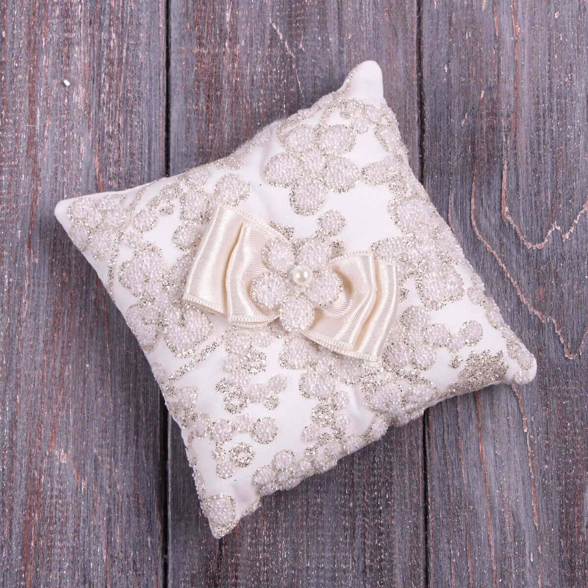 Christening Ceremony Pillow with floral embroidery and a bow on a wooden surface