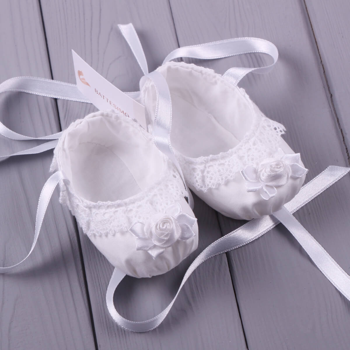 Christening Booties with lace details on a gray wooden surface