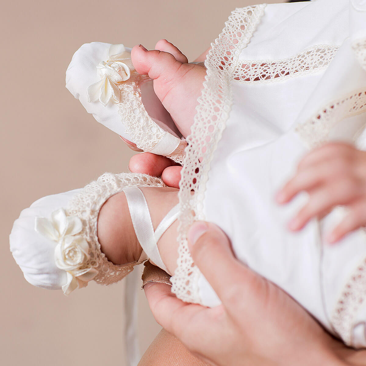 Baby's feet in Christening Booties with a neutral background