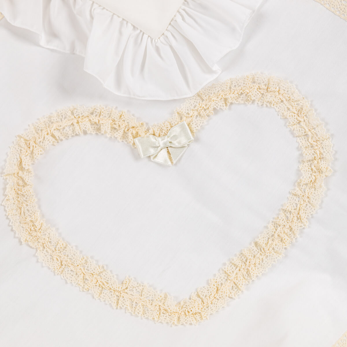 Heart-shaped baptism blanket with lace trim and a bow on a white background