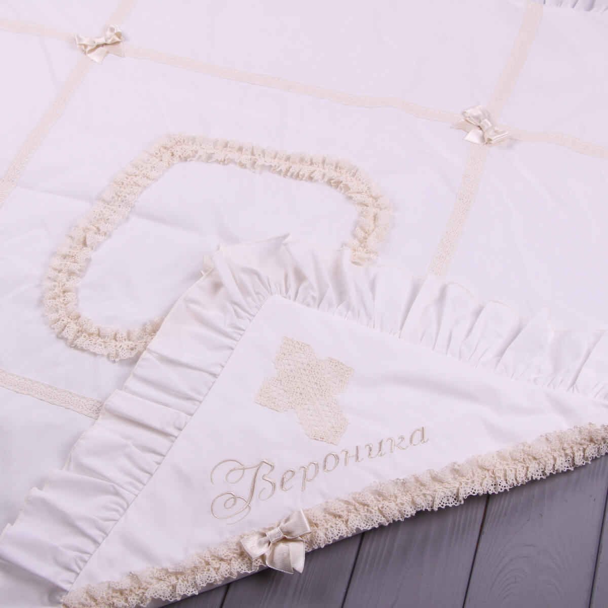White baptism blanket with decorative heart and embroidered name on a wooden surface