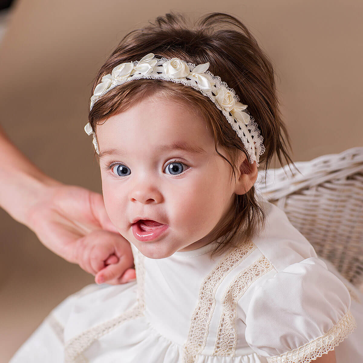 Baby wearing baby  headband and dress against a neutral background