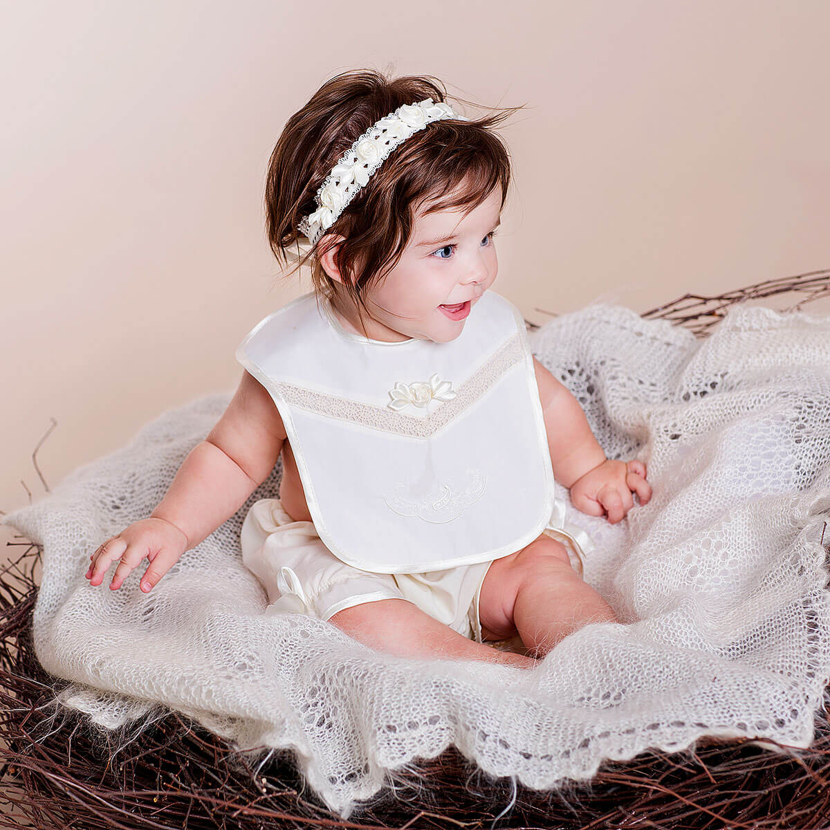 Baby in a Newborn Bib sitting on a textured surface with a neutral background