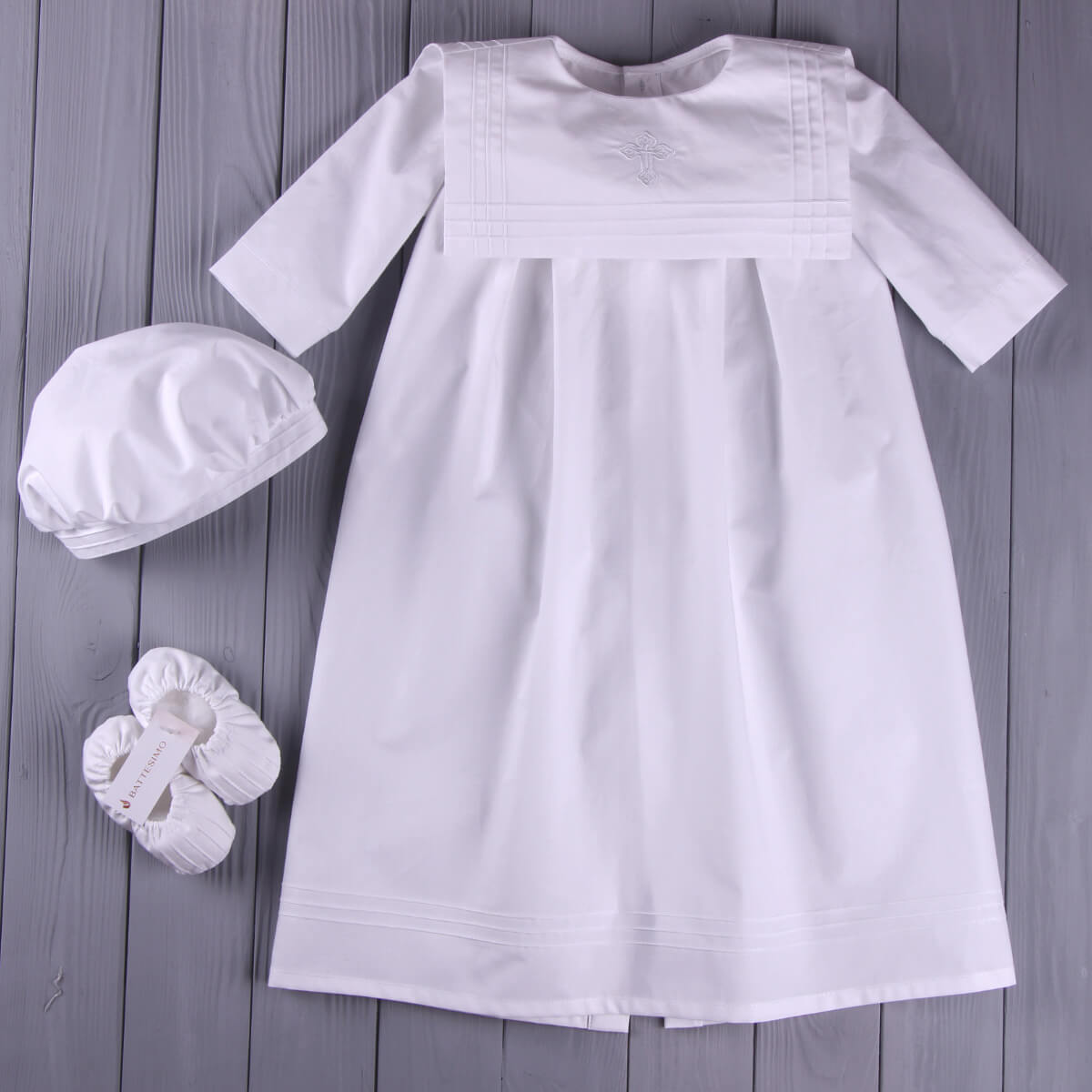 Christening Outfit with matching hat and booties on a wooden surface