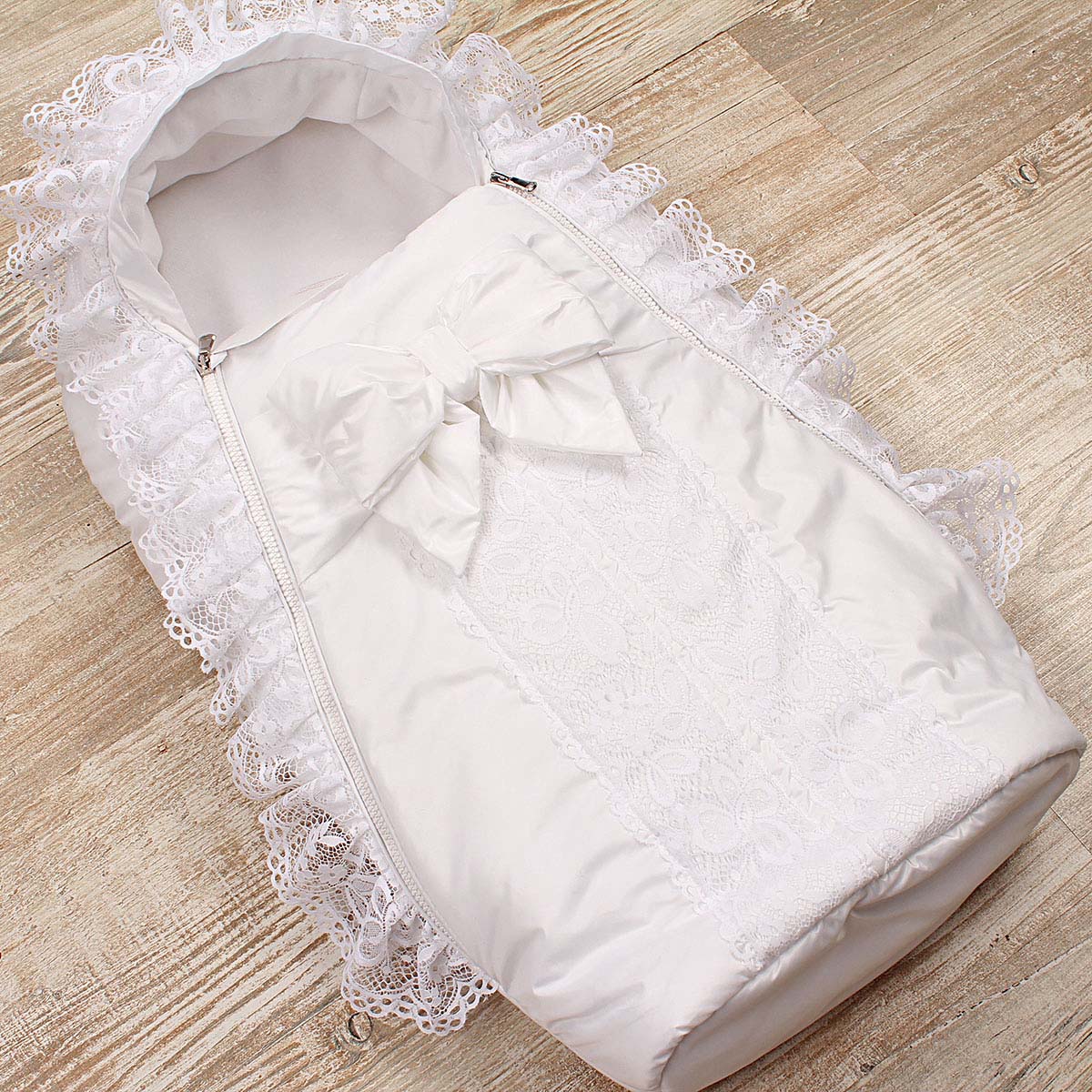 Newborn winter sleep sack with lace details on a wooden surface
