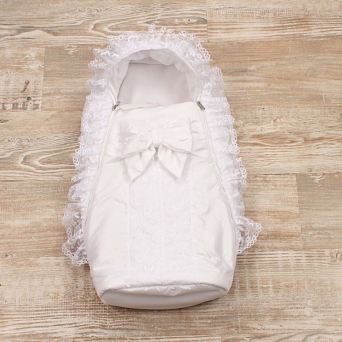 Newborn winter sleep sack with lace details on a wooden surface