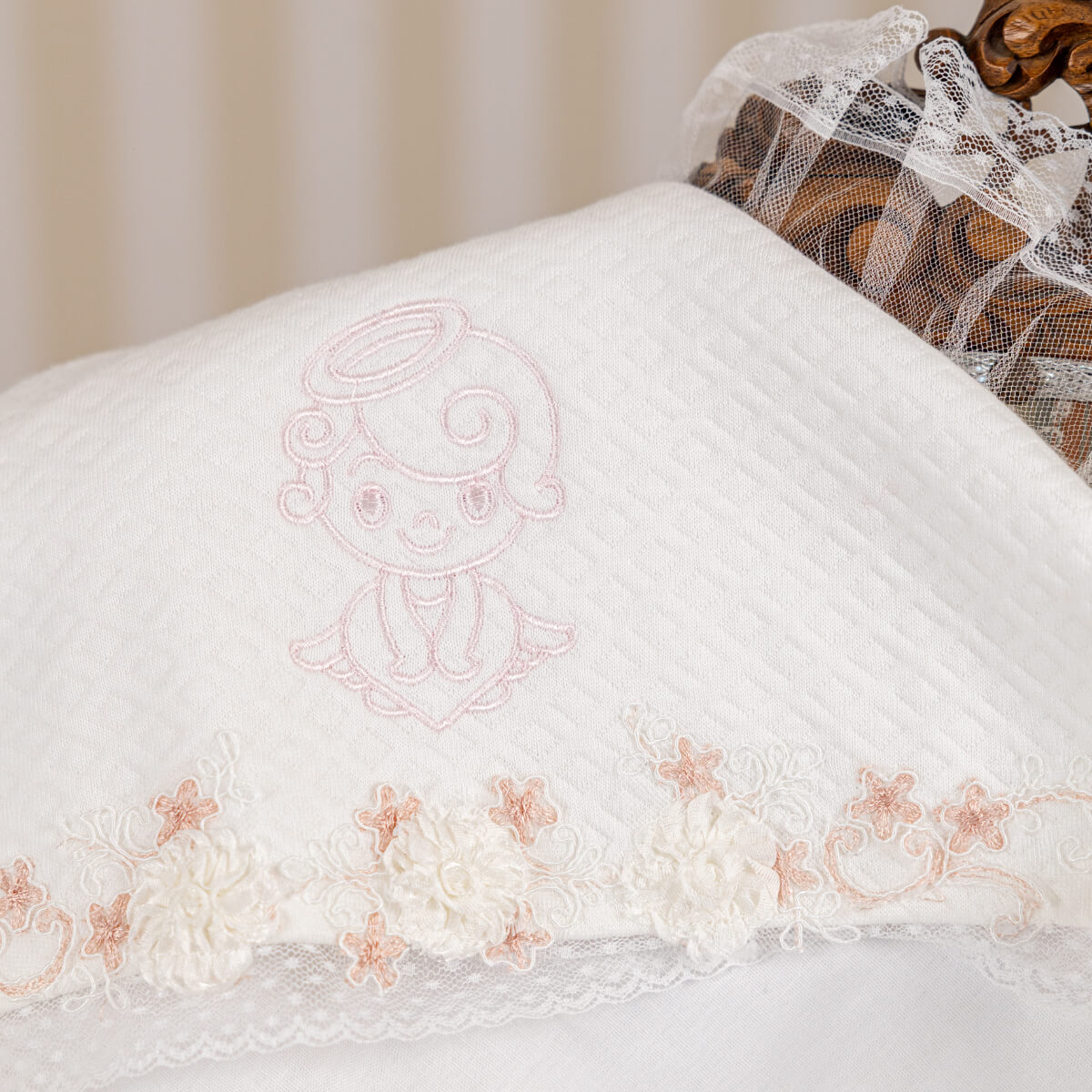 Embroidered angel design on a white fabric with floral patterns.