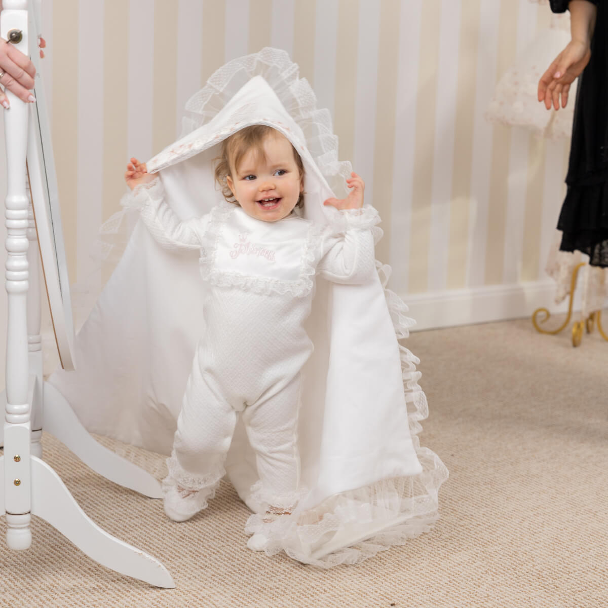Child in a white outfit with a lace baptism blanket for newborns