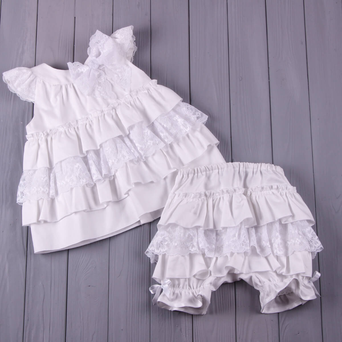 Christening Lace Dress and bloomers set on a wooden surface